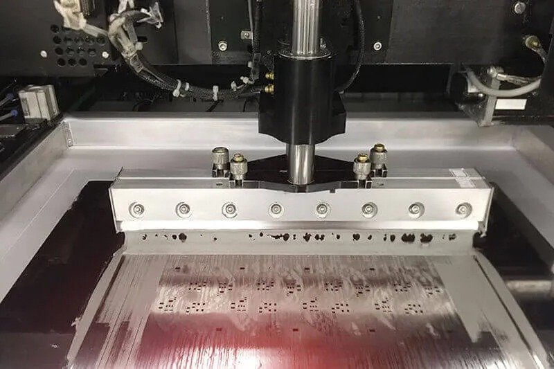  illustrating the solder paste printing process in PCB assembly, showing a squeegee applying solder paste through a stainless steel stencil onto the PCB pads.